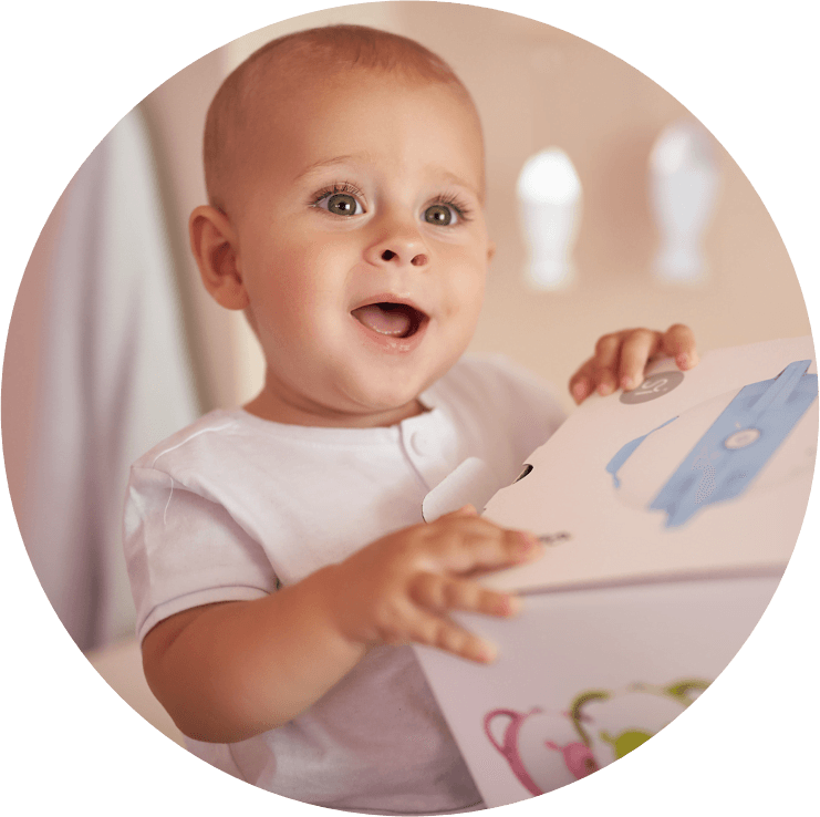 Ein faszinierter kleiner Junge hält eine Schachtel mit dem Nosiboo Pro elektrischen Baby Nasensauger in den Händen