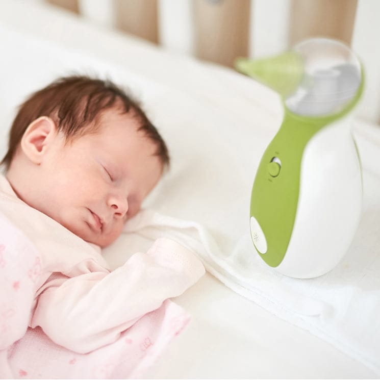 Ein Baby schläft friedlich im Babybett neben dem tragbaren Baby Nasensauger Nosiboo Go