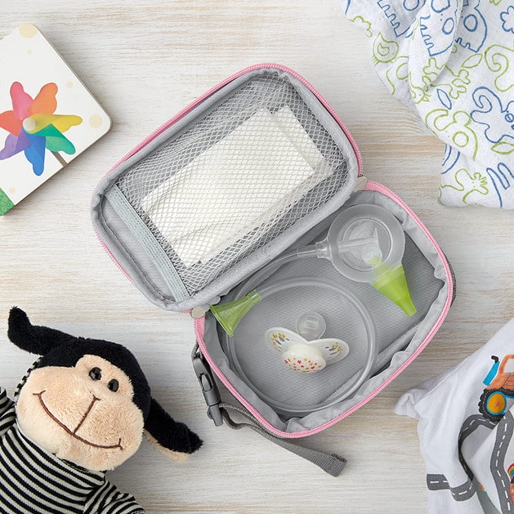 Eine geöffnete Nosiboo Bag Hygienetasche auf einem Tisch liegend bepackt mit dem Nosiboo Eco manuellen Baby Nasensauger und anderem Babyzubehör