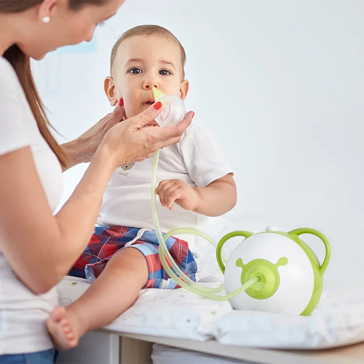 A woman clearing a boy's nose with the help of a baby nasal aspirator Nosiboo Pro