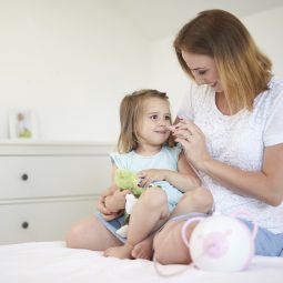 Öffnen Sie das Bild einer Mutter, die ihrer Tochter mit Hilfe des Nosiboo Pro elektrischen Baby Nasensaugers die verstopfte Nase reinigt